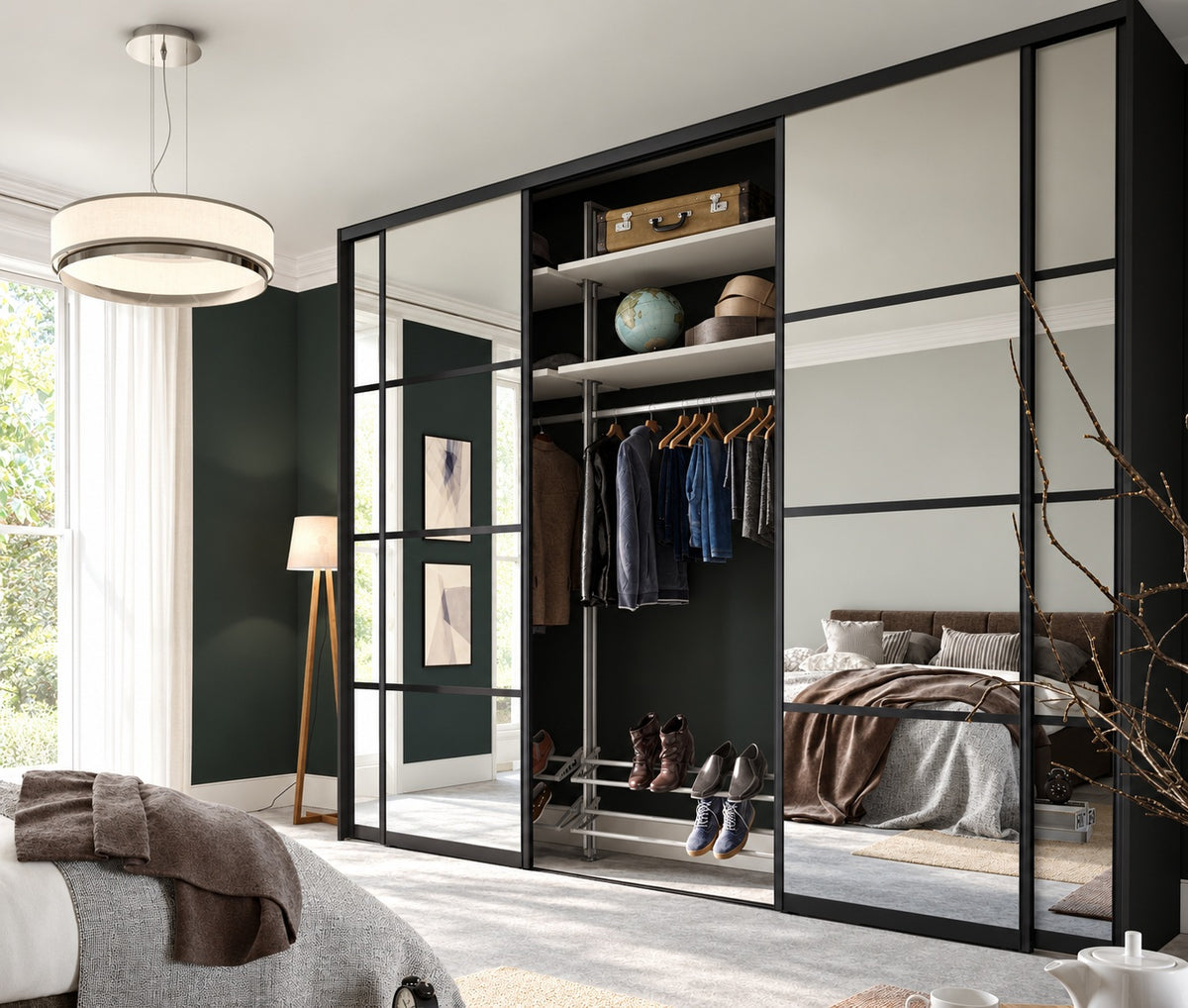 Black-framed mirrored sliding wardrobe with open hanging and shoe storage in a luxury bedroom